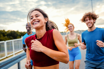 Smiling group of people running together on outdoor road.
