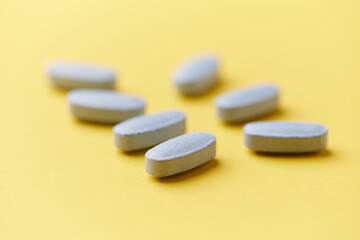 Multivitamin tablets on bright paper background. Close up. Copy space	