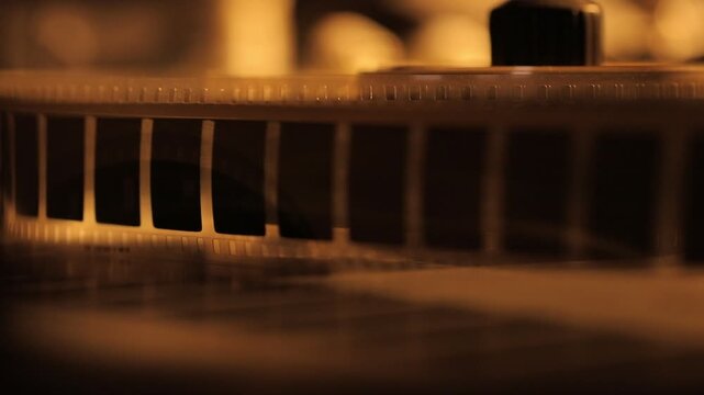 This video captures the intricate process of splicing film with a gloved hand. A close-up view reveals a metal splicing machine, with a roll of film being carefully maneuvered and joined.