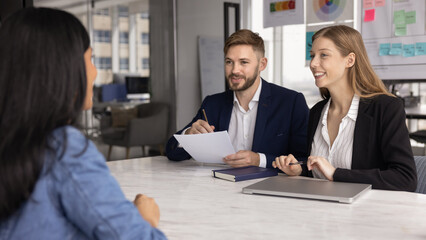 Diverse employers and job candidate talking at meeting table in company office, discussing resume, professional skills, vacancy requirements, hiring, onboarding, smiling, laughing