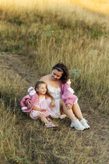 Fototapeta premium A young mother and daughter are hugging in nature among the mountains in beautiful identical sweaters