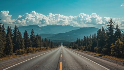 Fototapeta premium Unoccupied road through woodland and mountainous scenery beneath a vivid blue sky