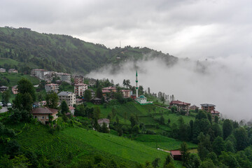 Fototapeta premium Fog rolling over the green hills surrounding a mosque and houses in Turkey