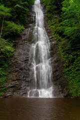 Obraz premium Scenic Tar waterfall cascading down rocky cliff into pond in lush green forest