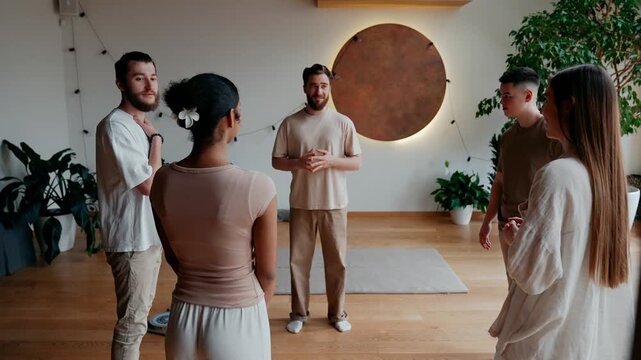 A group of four students and a male yoga mentor talk while standing in a circle