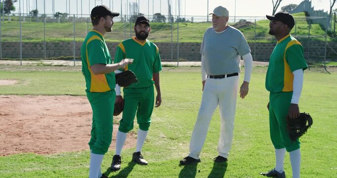 Coach stepping forward with Diverse male players making plan on ball field with gloves