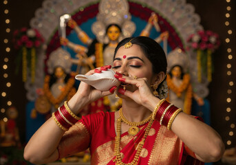 Closeup woman blowing shankh in temple lights