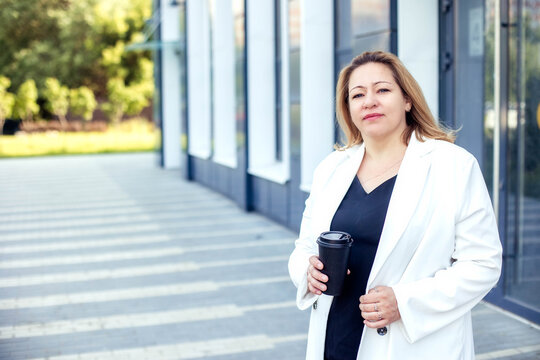 Attractive plus size businesswoman with a glass of coffee on the street of a modern city