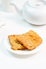 Two pieces of crispy fried tempeh coated in flour, a popular Indonesian street food known as 'tempe goreng balut tepung' or 'gorengan', served on a white plate.