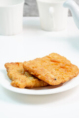 Two pieces of crispy fried tempeh coated in flour, a popular Indonesian street food known as 'tempe goreng balut tepung' or 'gorengan', served on a white plate.
