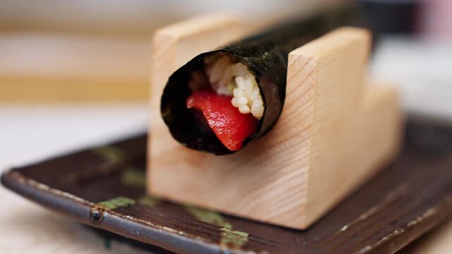 Close-up of an akami hand roll served in a refined restaurant setting, featuring lean tuna wrapped in crisp seaweed with seasoned rice. The vibrant red fish and elegant presentation.