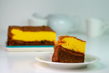A delicious slice of a two-layer sponge cake with yellow and chocolate layers on a simple white plate. A classic, homemade sweet treat for any occasion.