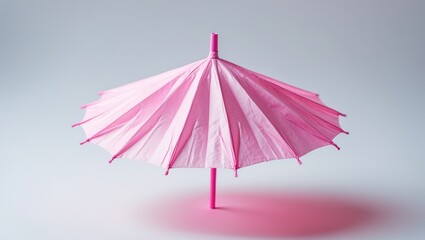 Pink paper umbrella set against a white backdrop