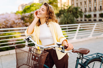 A cheerful tourist rides a bicycle along the sunny streets of the city. A beautiful woman in...