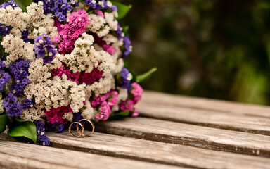 Colorful bridal bouquet resting on a rustic wooden bench, symbolizing romance and celebration. Vibrant wedding flowers placed outdoors, combining natural beauty with a touch of tradition.