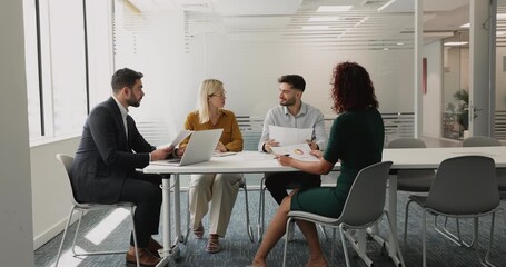 Four businesspeople participate in business meeting in modern office, presenting data or insights, analyze visual information displaying in charts, reviewing together financial performance or strategy - Powered by Adobe