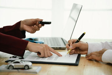 A businessman and client complete an agreement by signing documents for car insurance, loan, or rental, symbolizing finance, contract, policy, investment, purchase, legal paperwork, and secure ownersh