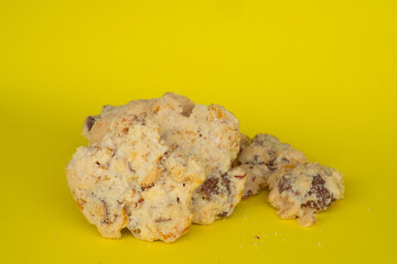 Homemade chocolate chip cookies with nuts, freshly baked and placed on a vibrant yellow background. The perfect rustic dessert or sweet snack.
