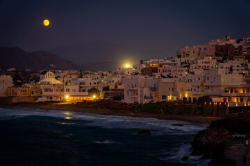 Obraz premium Naxos, Greece - Historical town illuminated at sunset with full blood moon in the sky