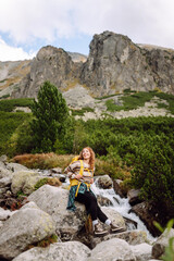 Naklejka premium A female hiker with a yellow hiking backpack on a hiking mountain trail on a sunny day. Beautiful woman enjoying mountain landscapes on a trip. Adventure concept, hiking. Active lifestyle.