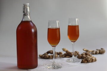 Ginger wine in clasp bottle and flutes with fresh root showing Indian wellness and artisanal heritage
