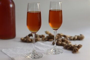 Ginger wine in clasp bottle and flutes with fresh root showing Indian wellness and artisanal heritage