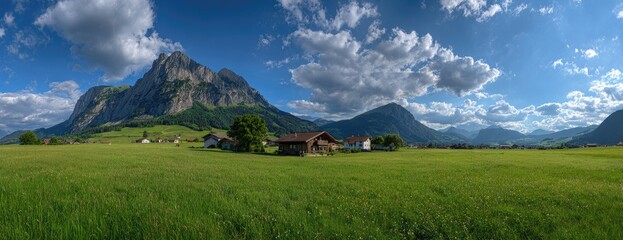 Panoramic view of a Swiss valley, with alpine mountains and meadows.  Wooden chalets dotted across a vibrant green field under a partly cloudy blue sky. Lush landscape stretches towards majestic peaks