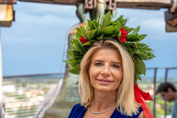 Proud graduate girl celebrating academic success with laurel garland near Pisa Tower landmark