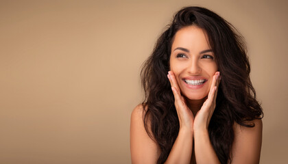 Happy beautiful millennial brunette half-naked woman with gorgeous long hair and glowing skin looking at copy space and smiling, isolated on beige background. Face care routine, skin treatment © Prostock-studio