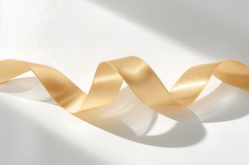 A close up shot of a golden ribbon gracefully curving across a pristine white surface with soft shadows