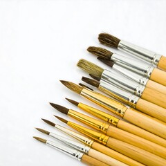 Fototapeta premium An array of paintbrushes with wooden handles and varying bristle types arranged on a white background