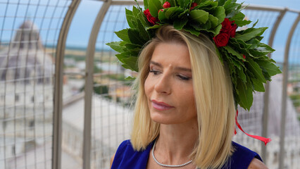 Proud graduate girl celebrating academic success with laurel garland near Pisa Tower landmark