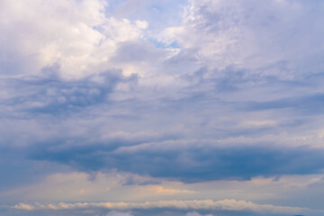 Mysterious clouds drift across a light blue sky at dusk revealing hints of sunlight and fantastic formations