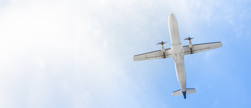 A plane flying through the sky against a blue sky, view from below. The concept of air travel is an airline ticket service. Flying high above the clouds, a commercial plane takes off on a bright