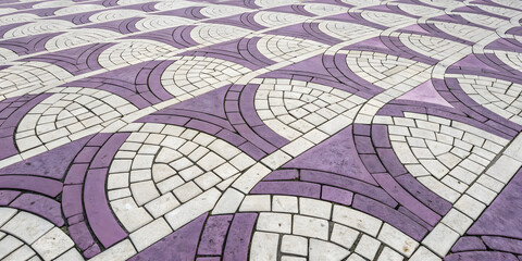 Obraz premium Purple and white decorative pavers forming elegant curved swirl patterns in alternating colors with intricate geometric mosaic design arrangement.
