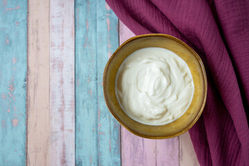 Porcelain bowl with natural yogurt on the wood table with napkin.