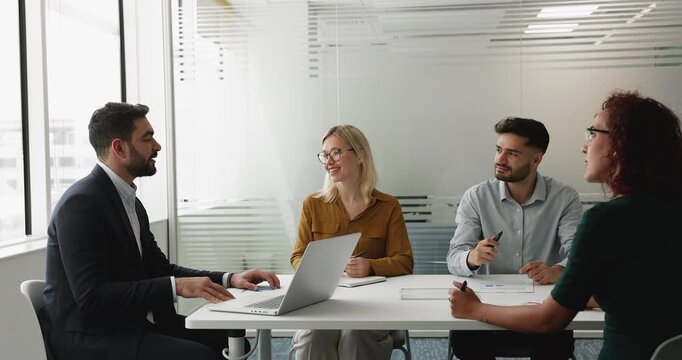Professional Arabian man in suit conduct meeting with shareholders or colleagues seated together around conference table in boardroom, share strategy, solution, coordinate team, work on joint project