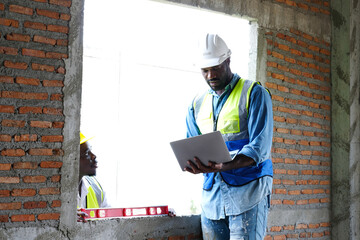Male engineer holding a laptop and working at a construction site &ndash; engineering and architectural concept.