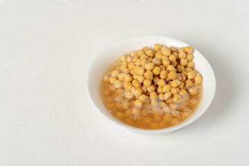 Soaked chickpeas. In a white bowl. On a white background. Ready to prepare any delicious recipe.