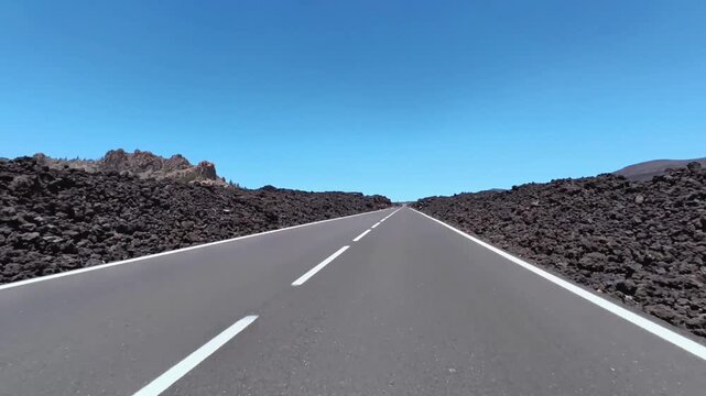 A picturesque road stretches across a breathtaking volcanic landscape under a stunningly clear blue sky