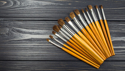 Natural wood paintbrush set with soft bristles arranged in fan shape on dark wooden surface, perfect for artistic creativity and detailed painting work