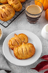 Pumpkin mini pies or hand pies with glass of coffee on a stone background. Traditional autumn dessert for Halloween and Thanksgiving. Copy space