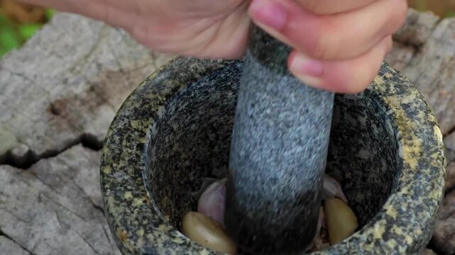 Pound garlic in a stone mortar.