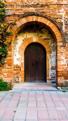Fototapeta premium Aged brick archway with weathered wooden door.