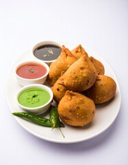 Crispy, golden-brown Indian snacks, served with dipping sauces, on a white plate