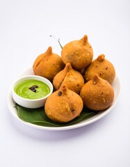 Golden fried savory pastries, likely Indian, served with a green chutney