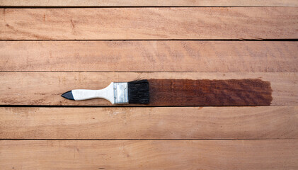 Paint brush apply varnish on new surface of lumber, wood product in top view and horizontal composition. Look wet, elegance and darker brown color to improve or coating stain grain surface.