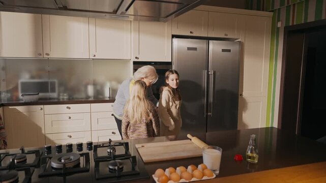 The grandmother ties an apron on her granddaughter and puts on another apron, and then they go to the table