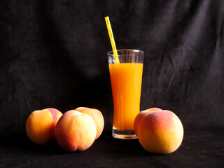 Peach juice in glass with peaches on black background. Healthy summer drink, organic fruit beverage concept.