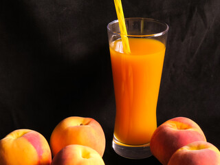 Peach juice in glass with peaches on black background. Healthy summer drink, organic fruit beverage concept.